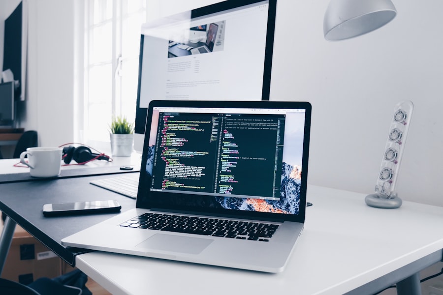 Ordinateur portable affichant du code, avec un site web en cours de conception en arrière-plan